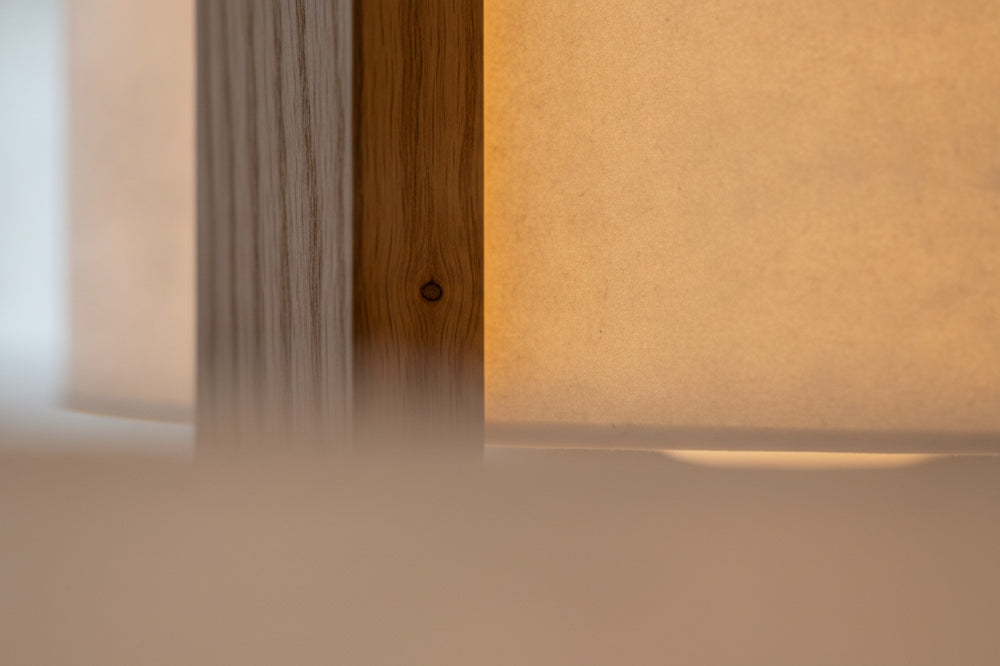 Oiled oak frame meeting the warm paper shade, in close detail